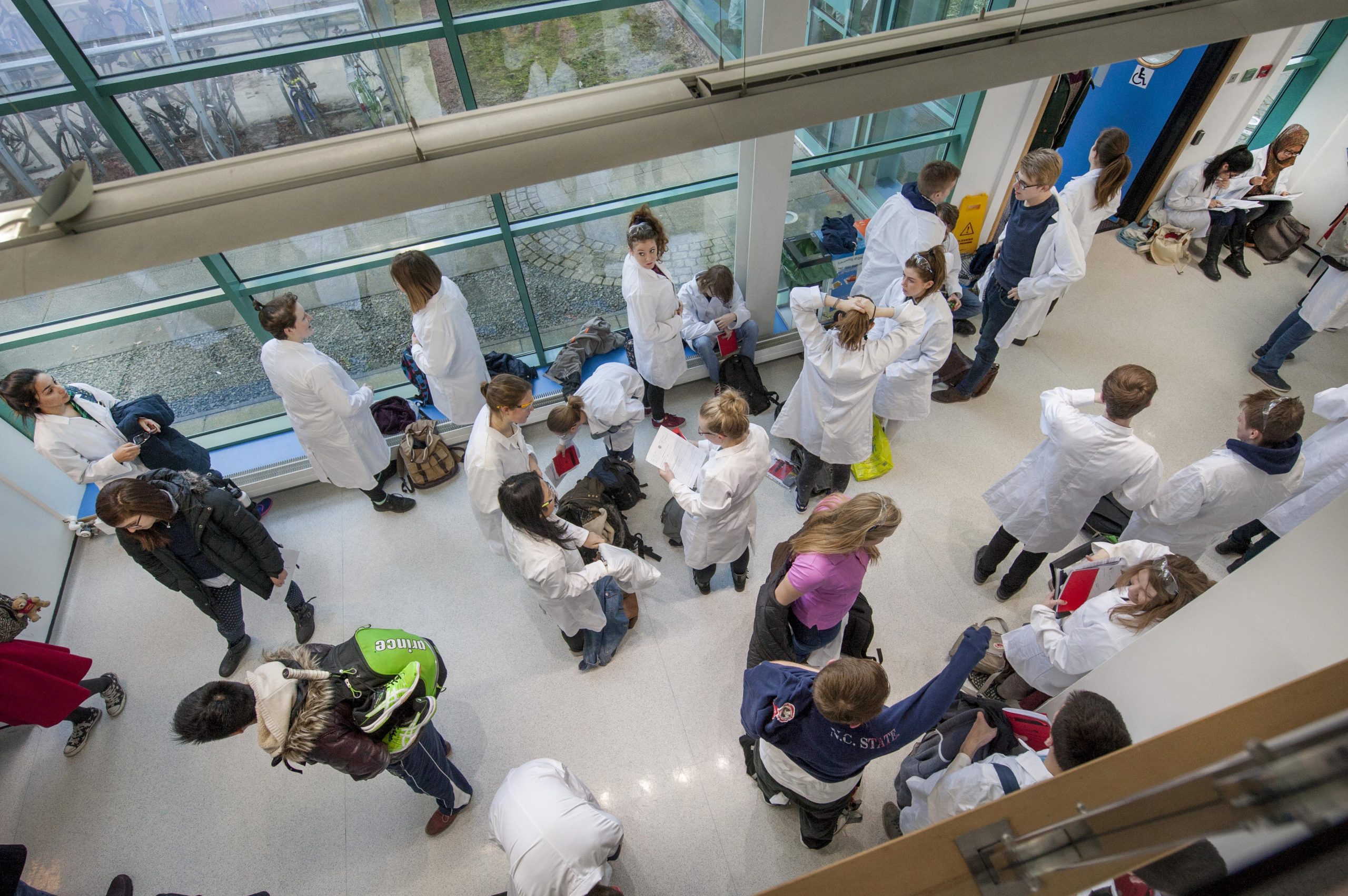 Photo of a crowd of students, most in lab coats, gathered outside a lab.