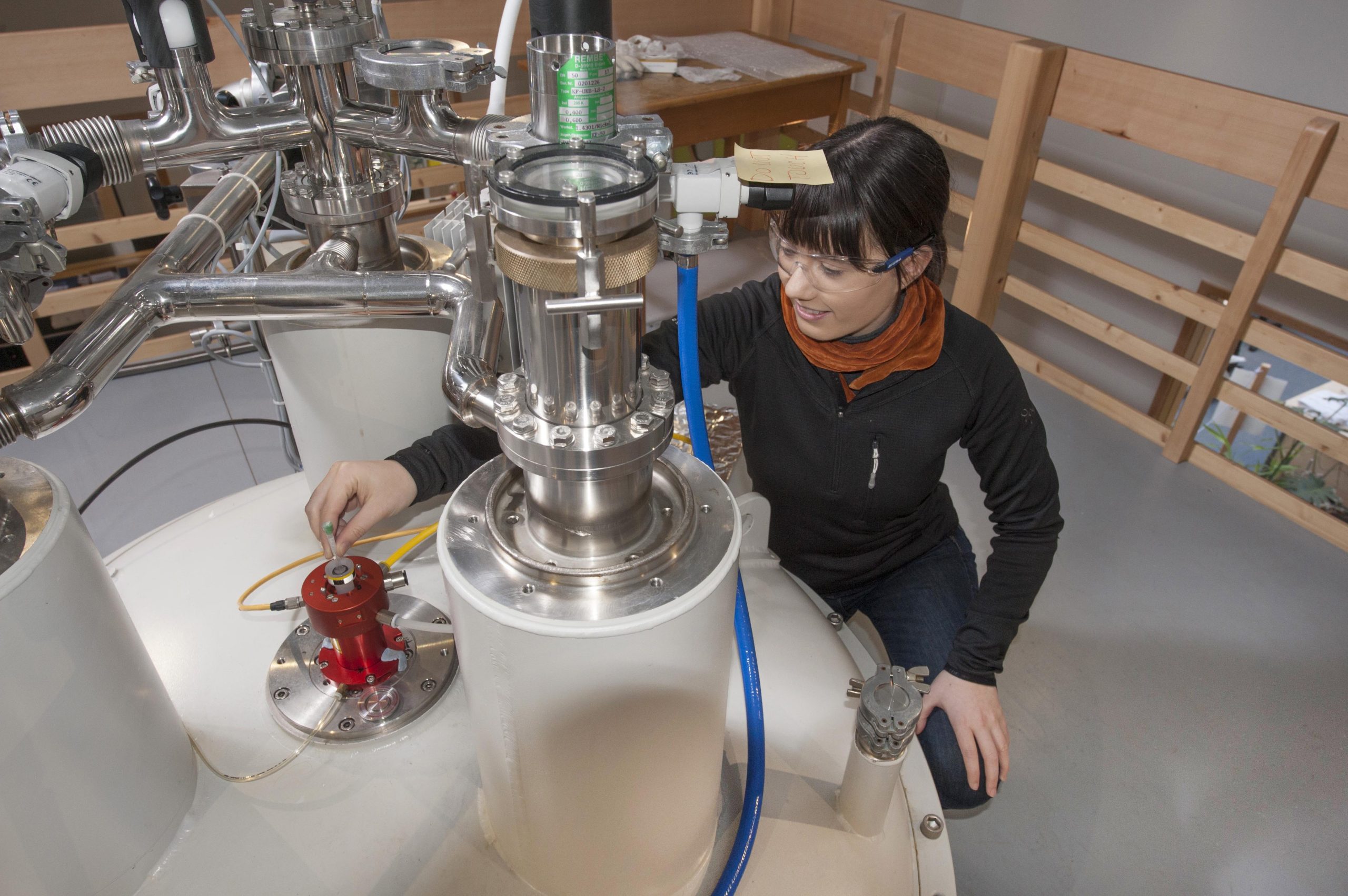 A young female researcher adds a sample to an NMR (Nuclear Magnetic Resonance) spectrometer