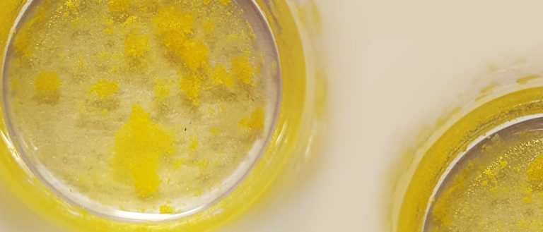 Photo of gold precipitating out of solution in two glass beakers.