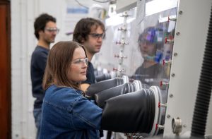 Three researchers working at a glove box in the Pyrochemical Research Laboratory.